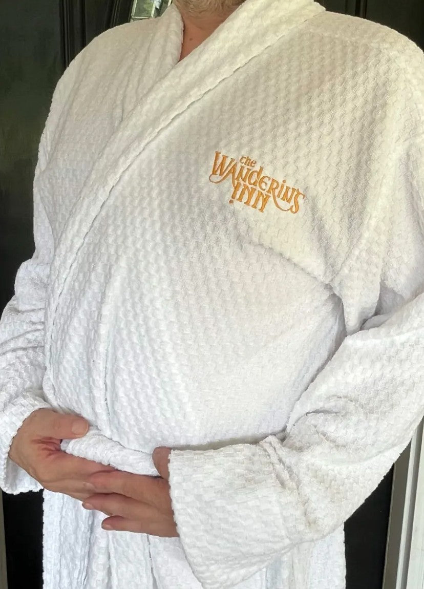The Wandering Inn bathrobe worn, white waffle texture with gold embroidered logo on the chest