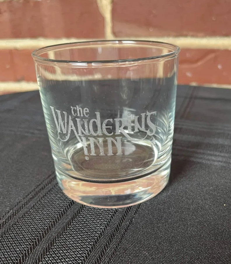 Glass on dark cloth by a brick wall, thick base and etching visible