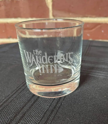 Glass on dark cloth by a brick wall, thick base and etching visible
