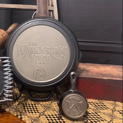 Set of cast iron skillets with The Wandering Inn branding on a rustic background.