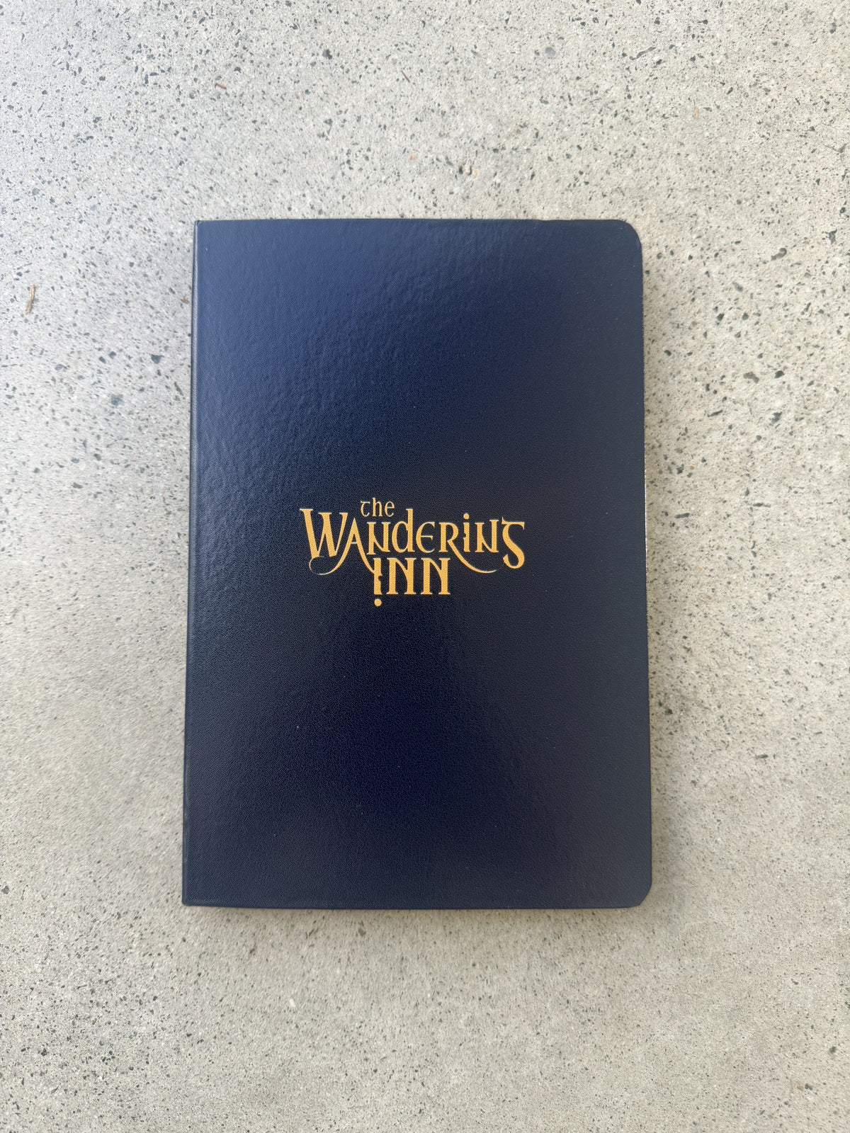 The Wandering Inn logo hardcover notebook, navy cover with gold foil wordmark