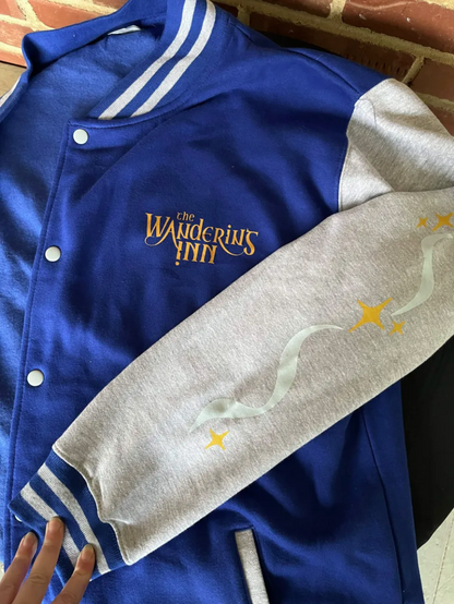 The Wandering Inn letterman jacket laid flat, showing the chest wordmark and the star print on the sleeve